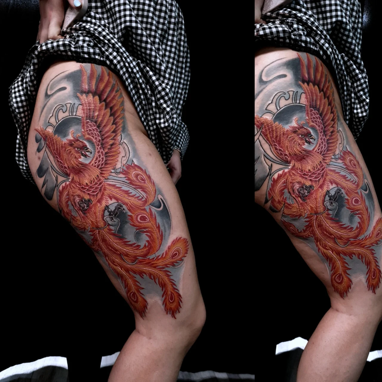 A vibrant tattoo of a fiery red and orange phoenix with outstretched wings covers a persons thigh, set against a smoky, black and gray background. The person is wearing a checkered garment pulled up to reveal the tattoo.