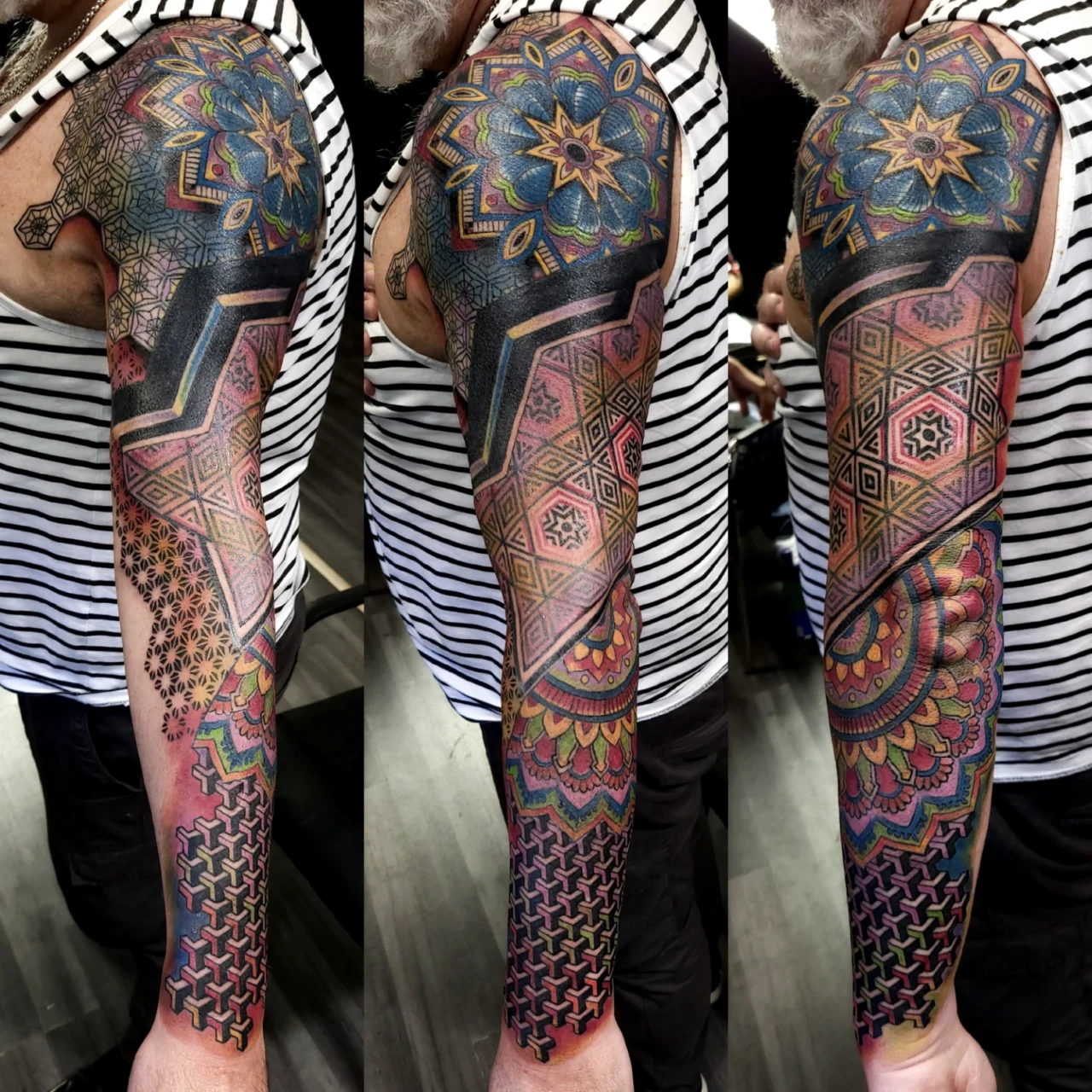 A mans arm with a colorful, intricate full-sleeve tattoo featuring geometric patterns, mandalas, and bold black lines. The tattoo covers the entire arm, blending shapes and detailed designs.