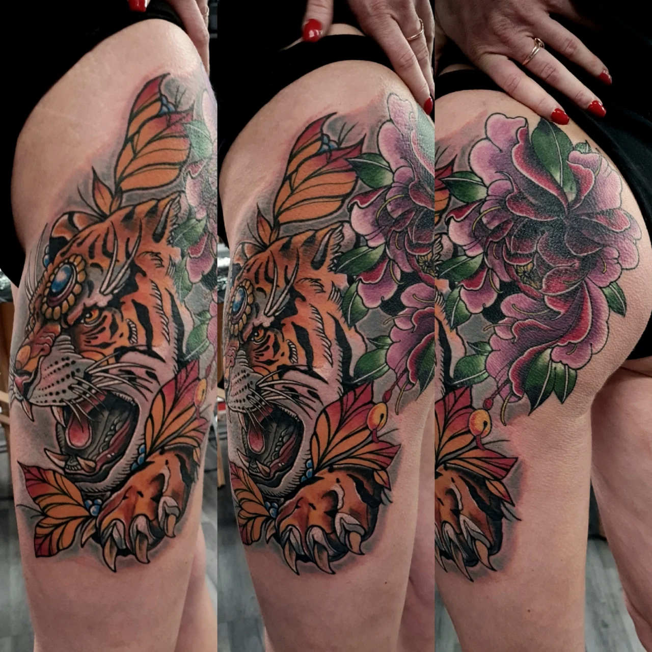 A colorful thigh tattoo featuring a roaring tiger with open jaws, wearing a jeweled headpiece, surrounded by orange leaves and large pink and purple flowers, extending onto the hip.