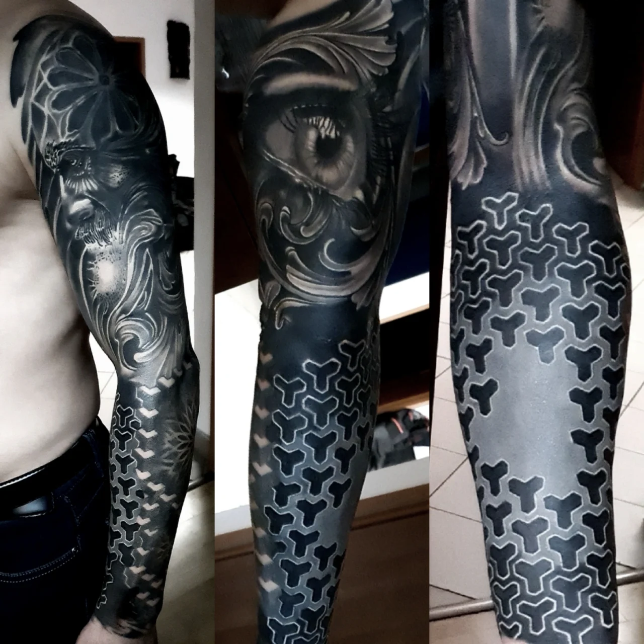 A tattooed arm sleeve featuring intricate black and gray designs, including geometric patterns, an eye, and various abstract elements, covering the entire arm from shoulder to wrist.