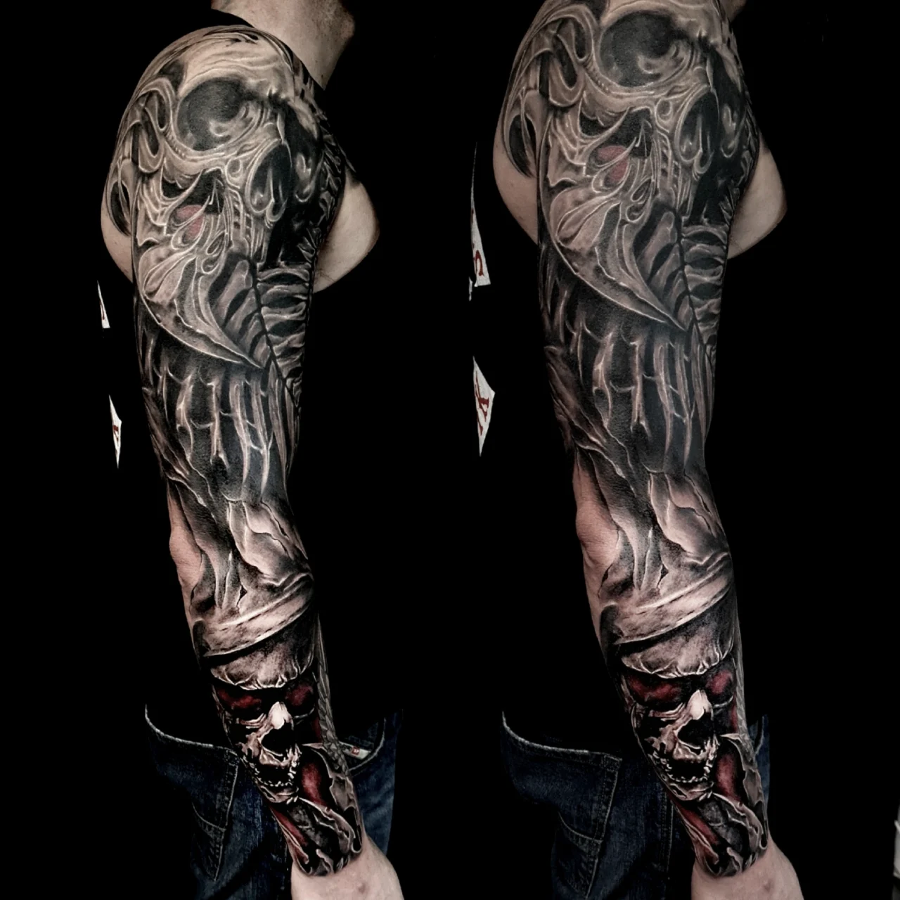 A person’s arm with a full-sleeve black and grey tattoo featuring detailed skulls, bones, and smoky effects, with some red accents, set against a dark background.